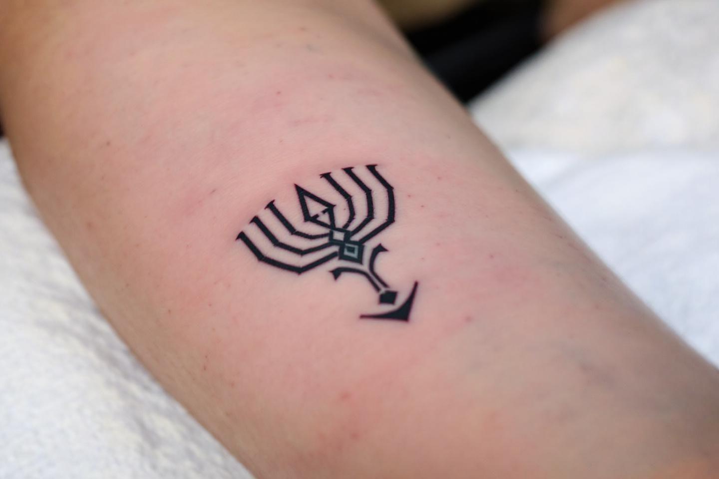 Petit tatouage noir d'araign&eacute;e g&eacute;om&eacute;trique sur peau claire